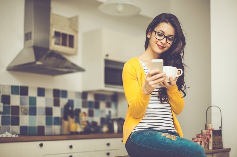 women sitting in the kitchen with phone and mug